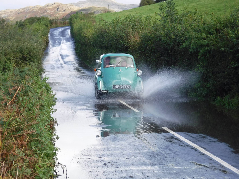 An Isetta drives through a flooded road on the 2017 rally